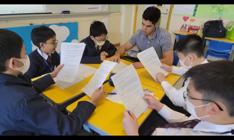 Students are practicing how to act with their radio drama scripts. They are very concentrated.