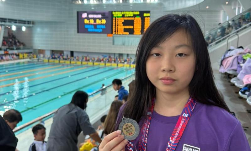 6A鍾天慧同學於港島西區小學校際游泳比賽獲女子甲組50米蛙泳殿軍，手持獎牌留影